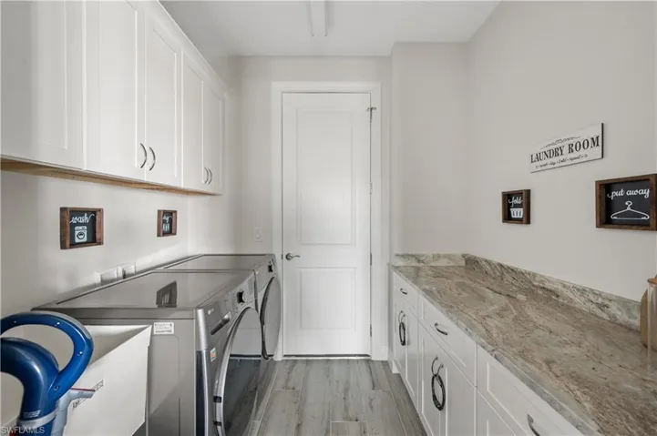 Laundry area with separate washer and dryer, light hardwood / wood-style flooring, and cabinets
