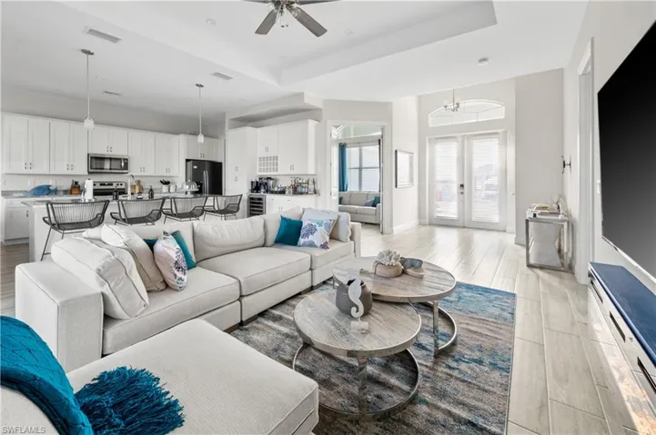 Living room with a tray ceiling and ceiling fan with notable chandelier