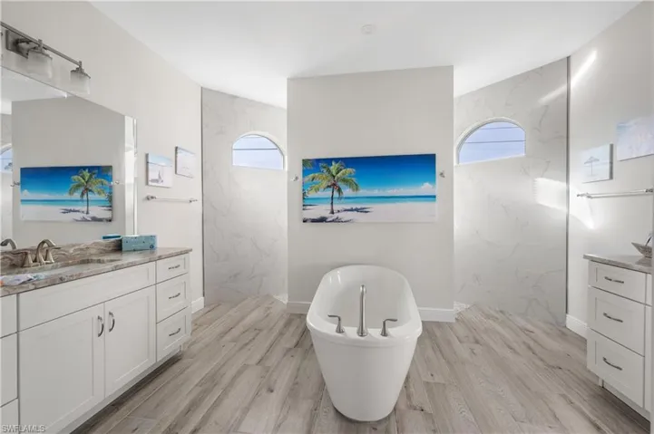 Bathroom with hardwood / wood-style flooring, vanity, and plus walk in shower