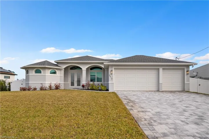 View of front of home featuring french doors, a front yard, and a garage