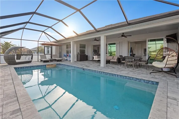 View of pool with a lanai, outdoor lounge area, ceiling fan, and a patio