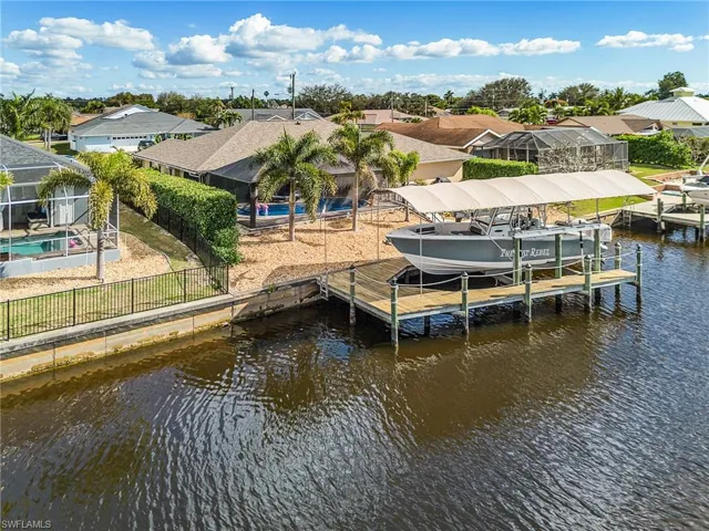 Dock area with boat lift, a fenced backyard, a water view, and a residential view