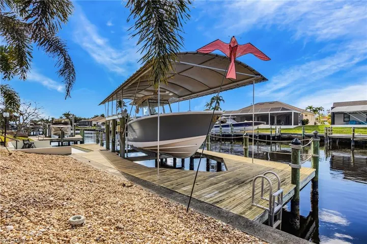 Dock featuring boat lift, a water view, and a residential view