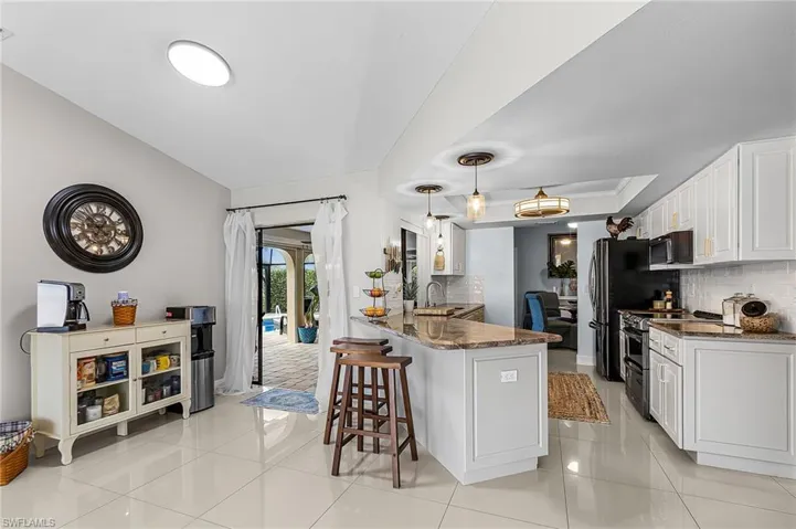 Kitchen featuring white cabinets, dark stone countertops, double oven range, and a kitchen bar