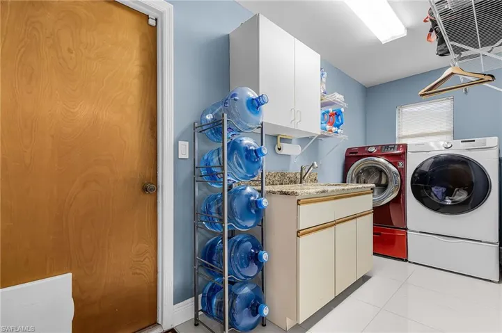 Laundry room with cabinet space, light tile patterned flooring, and washing machine and dryer