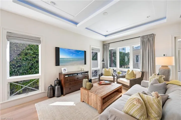 Living room with a tray ceiling and wood finished floors