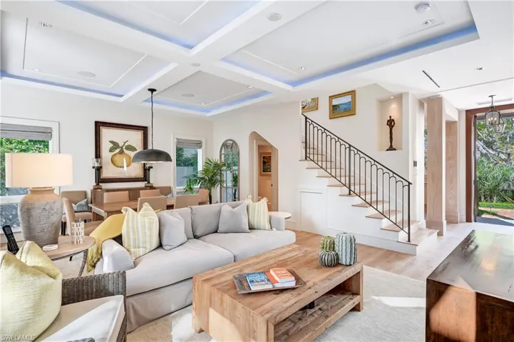 Living room with healthy amount of natural light, coffered ceiling, wood finished floors, and arched walkways