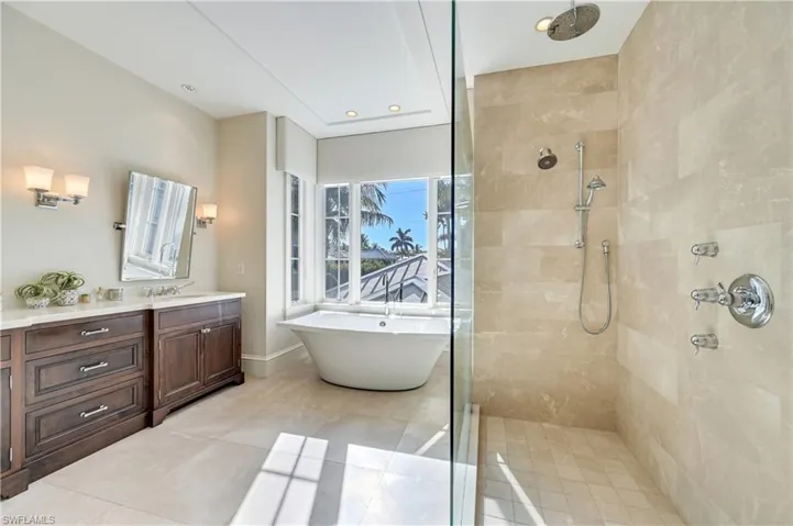Bathroom featuring tiled shower, vanity, a freestanding bath, recessed lighting, and light tile patterned flooring