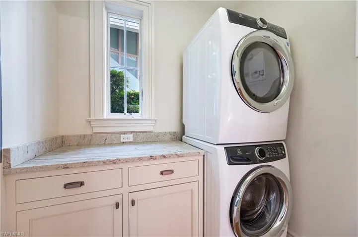 Laundry room with stacked washer / drying machine and cabinet space