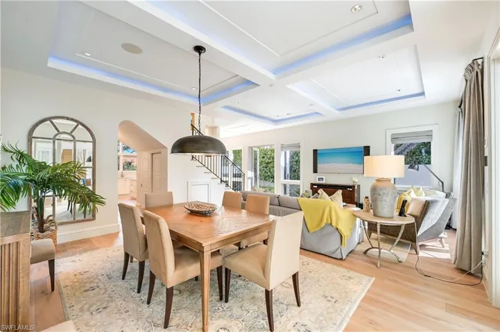Dining room with light wood-type flooring, healthy amount of natural light, arched walkways, coffered ceiling, and a raised ceiling