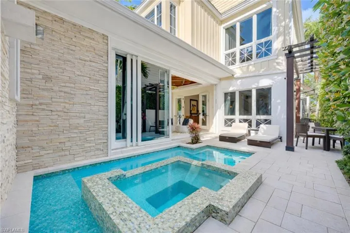 Rear view of property featuring a patio, a pool with connected hot tub, a ceiling fan, and outdoor dining space