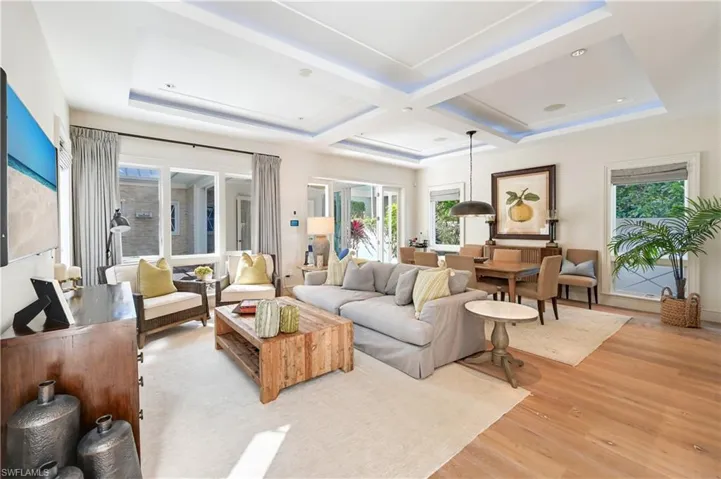 Living room featuring light wood-type flooring, coffered ceiling, and healthy amount of natural light