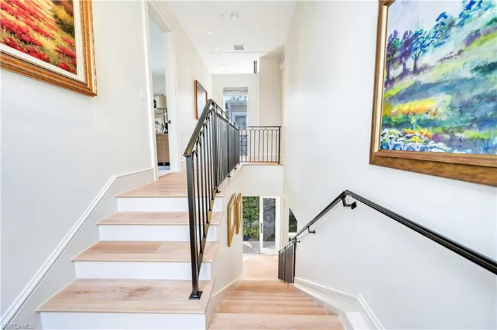Stairway with wood finished floors, a high ceiling, and recessed lighting