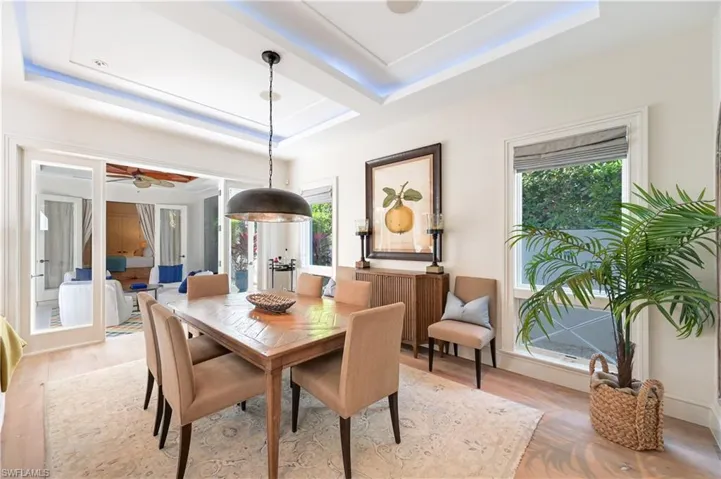 Dining area featuring light wood finished floors, a raised ceiling, and ceiling fan