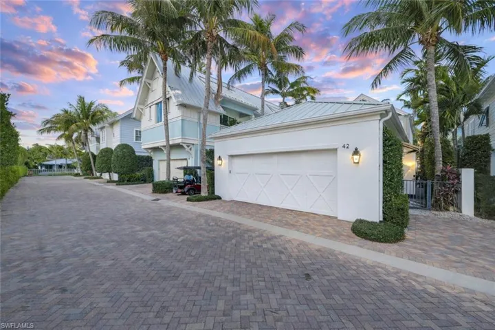 View of front facade with stucco siding, a garage, a metal roof, and decorative driveway
