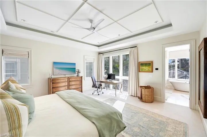 Bedroom featuring a raised ceiling, ceiling fan, and an office area