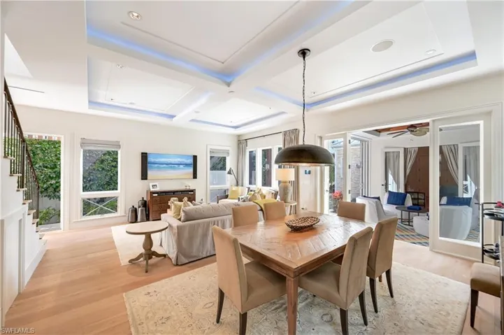 Dining space featuring light wood-style floors, coffered ceiling, plenty of natural light, ceiling fan, and a raised ceiling