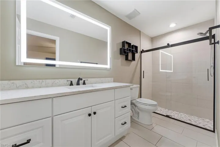 Bathroom featuring a stall shower, vanity, and light tile patterned flooring