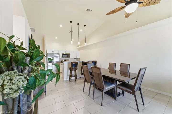 Dining area with lofted ceiling, recessed lighting, light tile patterned floors, and ceiling fan