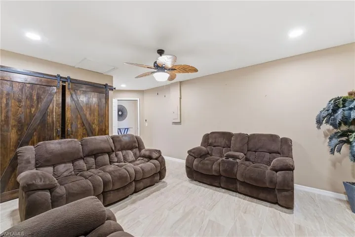 Living area featuring a barn door, ceiling fan, and recessed lighting