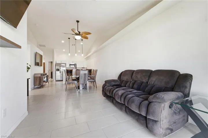 Living room with a ceiling fan, recessed lighting, light tile patterned flooring, and lofted ceiling