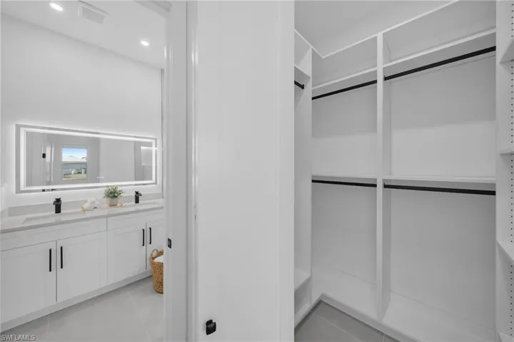 Walk in closet with light tile patterned floors and a sink