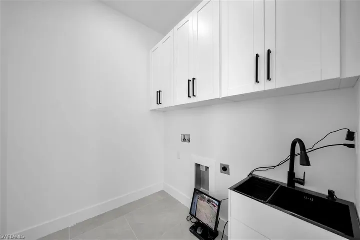 Laundry room featuring hookup for an electric dryer, washer hookup, light tile patterned floors, and cabinet space