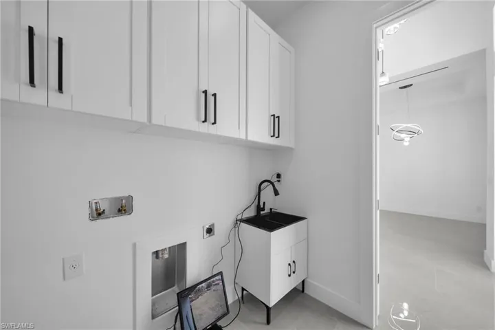 Laundry area with cabinet space, electric dryer hookup, light tile patterned floors, and hookup for a washing machine