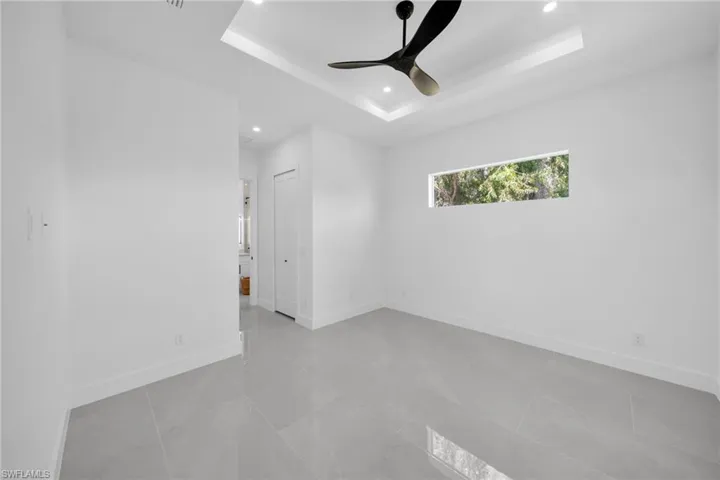 Unfurnished room with ceiling fan, recessed lighting, and a tray ceiling