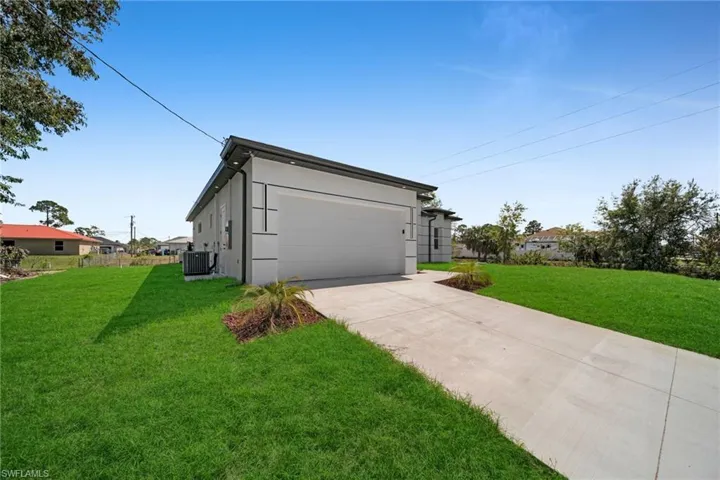 View of side of home with a lawn, a garage, driveway, and stucco siding