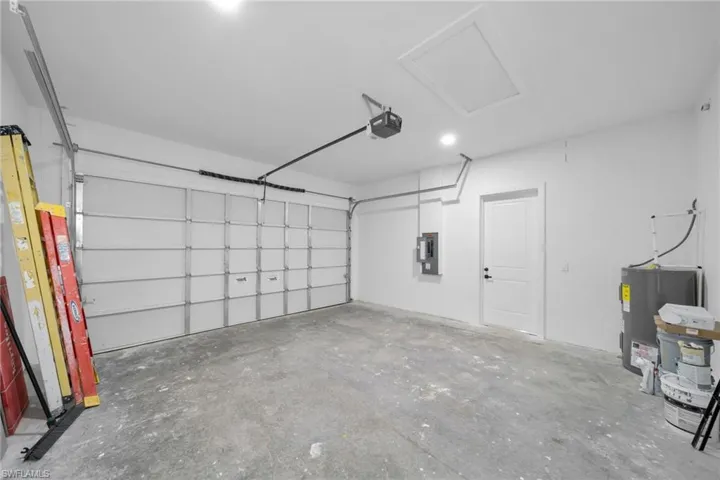 Garage featuring electric water heater and electric panel
