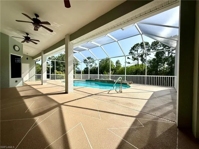 View of swimming pool with a patio area, ceiling fan, and glass enclosure