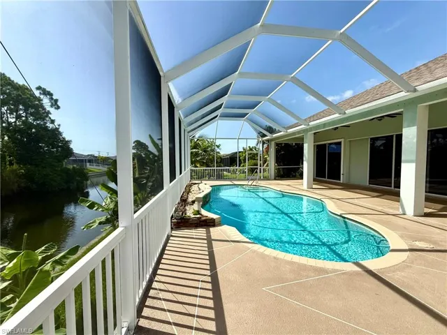 View of swimming pool with a water view, a patio, and glass enclosure