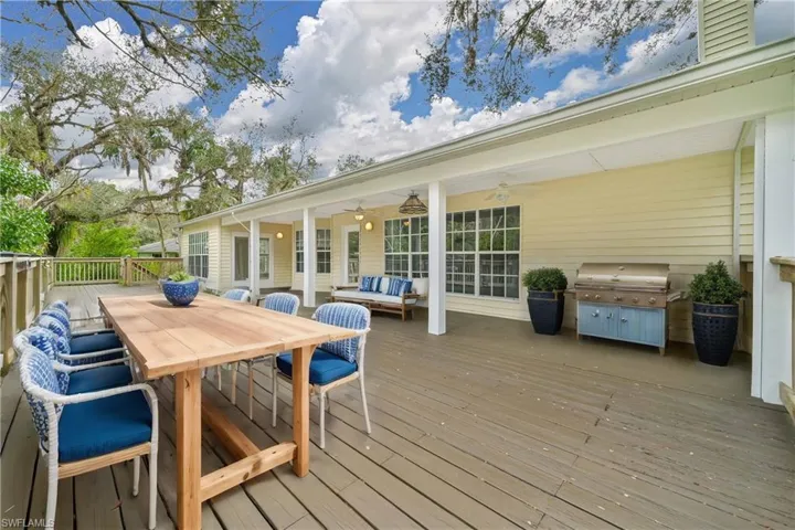 Wooden terrace featuring area for grilling, an outdoor hangout area, and ceiling fan