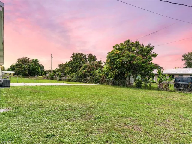 Expansive lawn area with mature trees and a concrete pad
