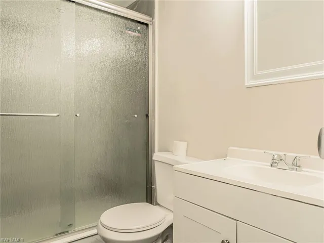 Bathroom featuring a sliding glass shower enclosure, white vanity with integrated sink, chrome faucet, and framed mirror