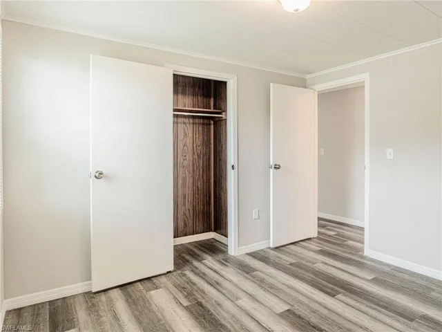 Room featuring wood-finish flooring, light grey painted walls, white trim, and a white ceiling