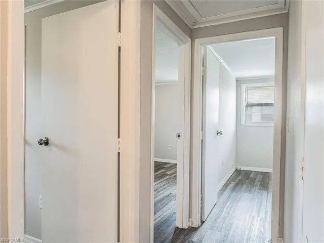 Hallway featuring white trim, gray walls, and wood-finish flooring