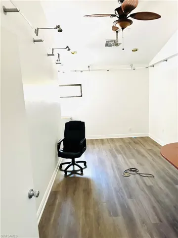 Unfurnished office with hardwood / wood-style flooring, lofted ceiling, and ceiling fan
