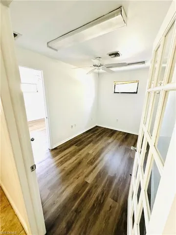 Empty room with dark hardwood / wood-style floors and ceiling fan