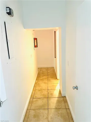 Hall with light tile patterned flooring and electric panel