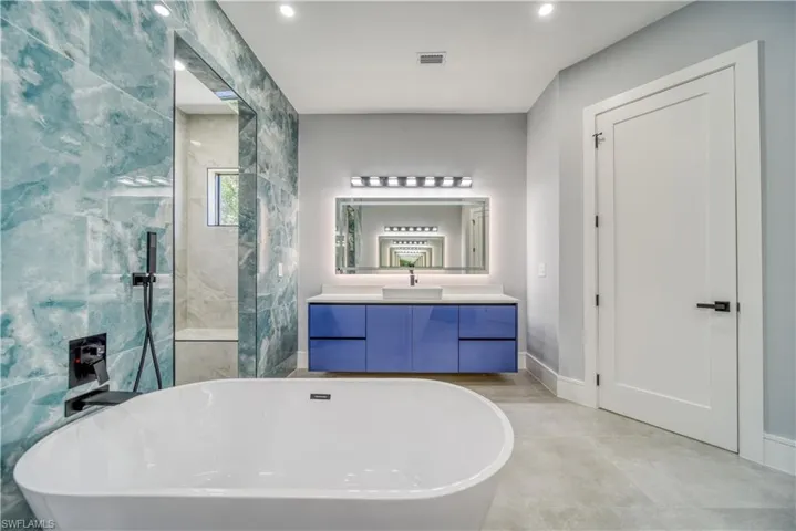Master Bathroom featuring vanity, a freestanding tub, visible vents, and walk in shower