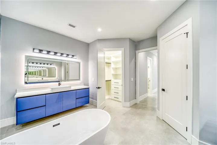 Master Bathroom with a freestanding tub, visible vents, a walk in closet, and vanity