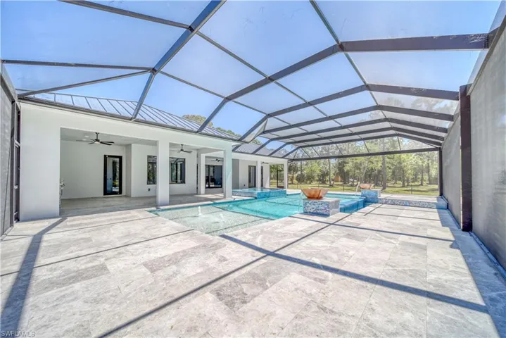 View of swimming pool with screen enclosure, a patio area, a pool with connected hot tub, and ceiling fan