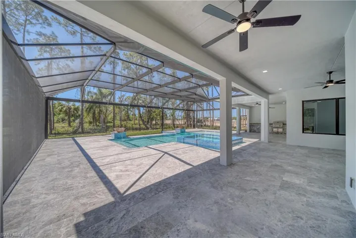 View of pool featuring screen enclosure, a patio, a ceiling fan, and a pool with connected hot tub