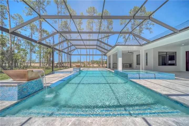 View of pool featuring screen enclosure, a patio, a ceiling fan, and a pool with connected hot tub