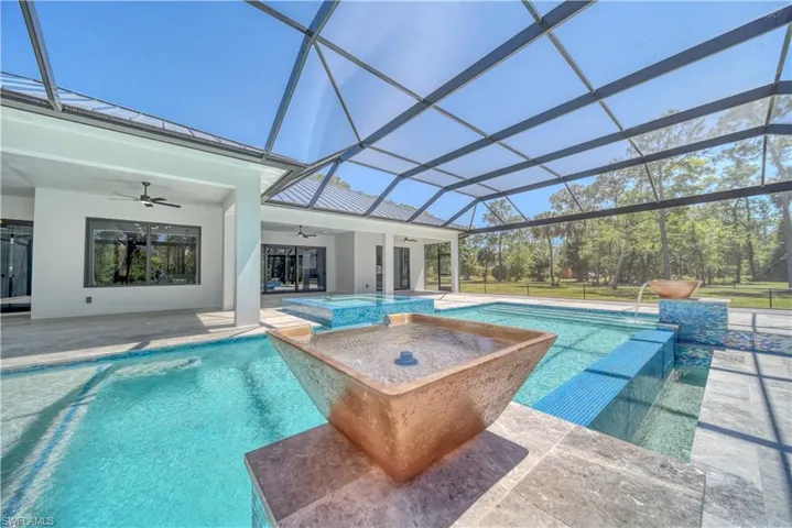 View of pool featuring 2 water feature bowls,  ceiling fan, a pool with connected hot tub, a lanai, and a patio area