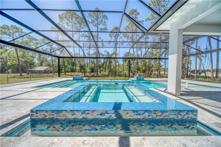 View of pool featuring a patio area, a pool with connected hot tub, and a lanai