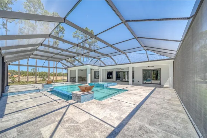 View of pool with screen enclosure, a pool with connected hot tub, a ceiling fan, and a patio