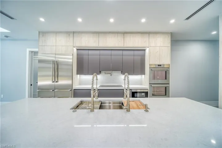 Kitchen with Thermador stainless steel appliances, light quartz  stone countertops, 2 faucet sink and modern cabinets